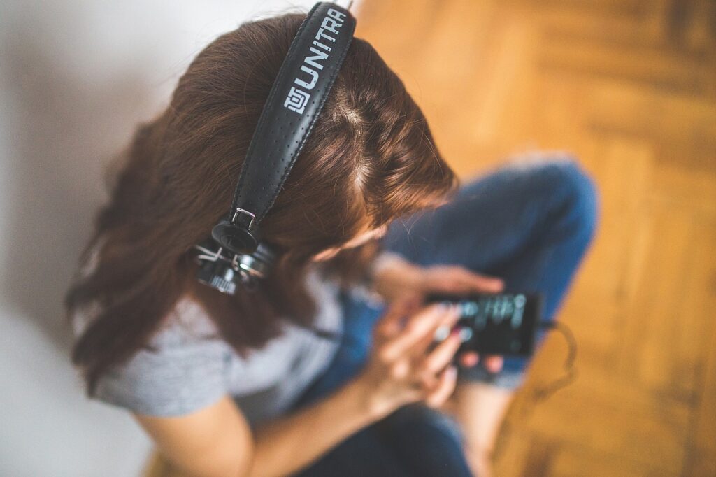 Photo of woman wearing headphones and listening to a podcast